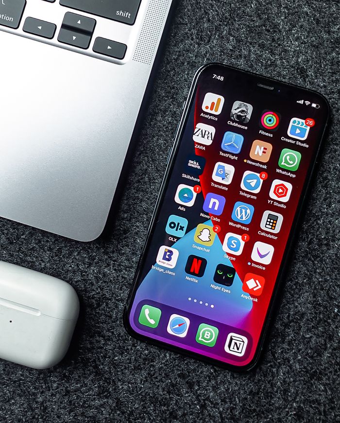 Flat lay of a smartphone, laptop, and earphones on a grey surface. Perfect for tech and gadget themes.